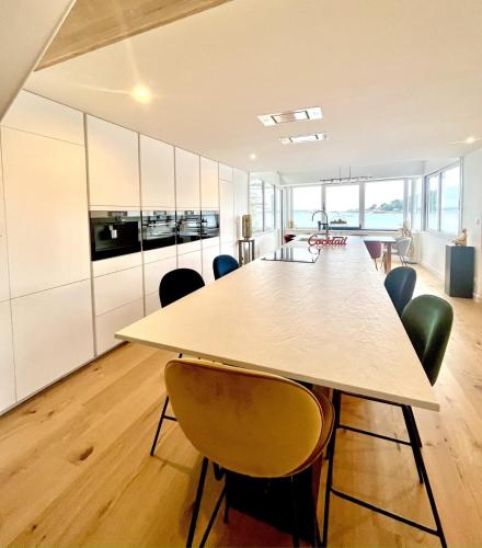 une cuisine ouverte et une salle à manger avec une table et des chaises dans l'établissement Évasion Prestige sur l'Île Koeur, à Lézardrieux