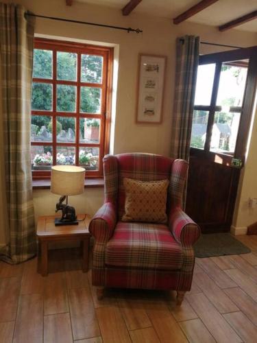 a living room with a chair and a lamp and windows at 1 Bed cottage The Stable at Llanrhidian Gower with sofa bed for additional guests in Swansea