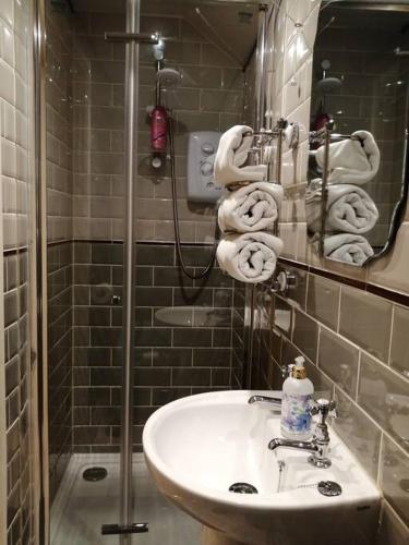 a bathroom with a sink and a mirror and towels at 1 Bed cottage The Stable at Llanrhidian Gower with sofa bed for additional guests in Swansea