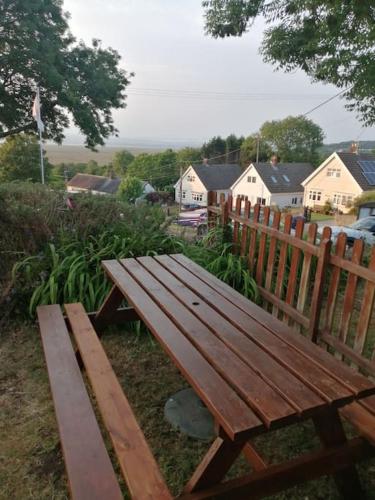 a wooden bench sitting next to a wooden fence at 1 Bed cottage The Stable at Llanrhidian Gower with sofa bed for additional guests in Swansea