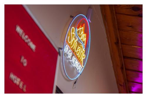 a neon sign on the wall of a restaurant at Shivalik River Retreat in Almora