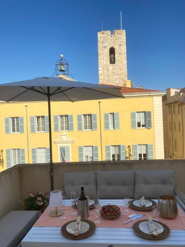 - une table avec des verres à vin et un parasol sur le balcon dans l'établissement Enjoy Antibes, à Antibes