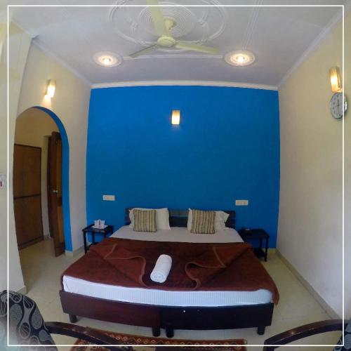 a bedroom with a large bed with a blue wall at Shivalik River Retreat in Almora