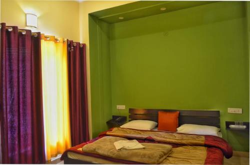 a bedroom with two beds and a green wall at Shivalik River Retreat in Almora