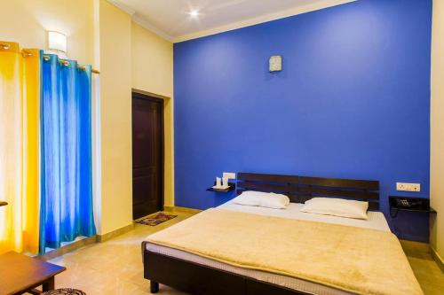 a bedroom with a blue wall and a bed at Shivalik River Retreat in Almora