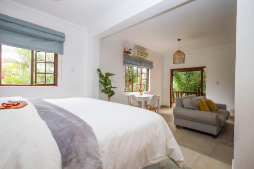 a white bedroom with a bed and a chair at The Blue Door Guesthouse in East London