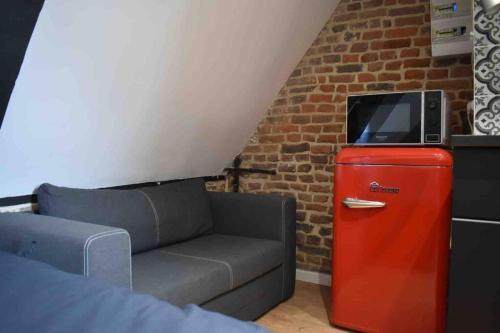 a living room with a couch and a tv on a red refrigerator at Charmant Studio au Cœur de Béthune in Béthune