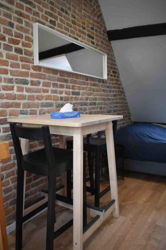 une table avec deux chaises et un miroir sur un mur de briques dans l'établissement Charmant Studio au Cœur de Béthune, à Béthune
