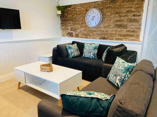 a living room with a couch and a clock on a wall at The Mill Stylish Rural Apartment with Beautiful Views in Welsh Newton Common