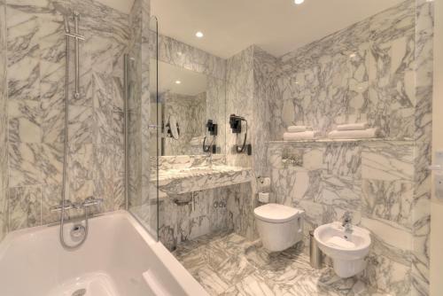 a bathroom with a tub and a sink and a toilet at Westminster Hotel & Spa Nice in Nice