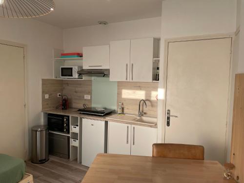 - une cuisine avec des placards blancs, un évier et une table dans l'établissement AlloAppartMeublé_Le cosy, à Houilles