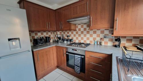 a kitchen with wooden cabinets and a stove top oven at 3-Bedroom Family Holiday Home in Skegness