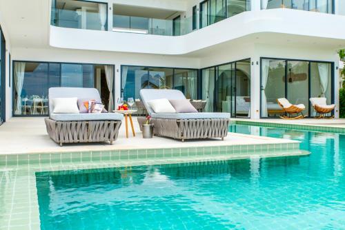 a swimming pool with two chairs next to a house at 5House:A luxury beachfront villa on Samui 滨海5卧室别墅 in Hua Thanon Beach