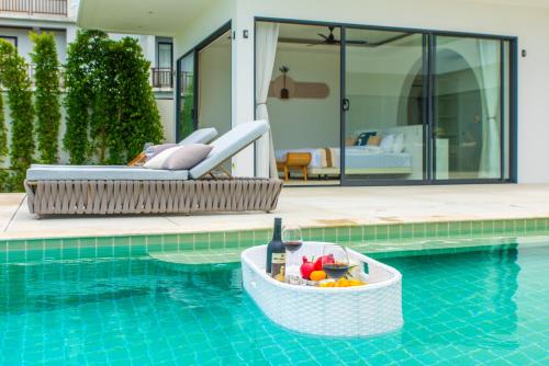 a bottle of wine and a basket of fruit in a swimming pool at 5House:A luxury beachfront villa on Samui 滨海5卧室别墅 in Hua Thanon Beach