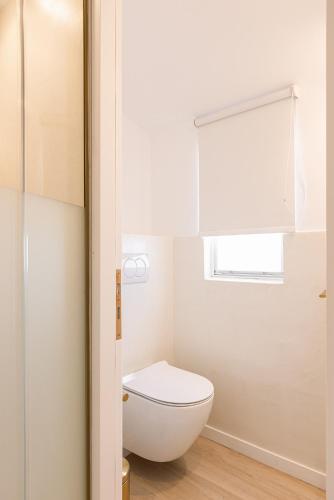 a bathroom with a white toilet and a window at Potokaki Beachfront Hotel in Pythagoreio