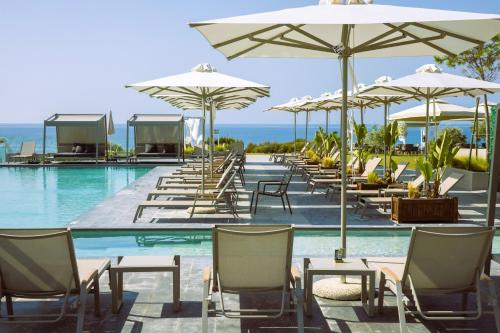 a pool with tables and chairs and umbrellas at Anasa Luxury Resort in Elaiokhórion