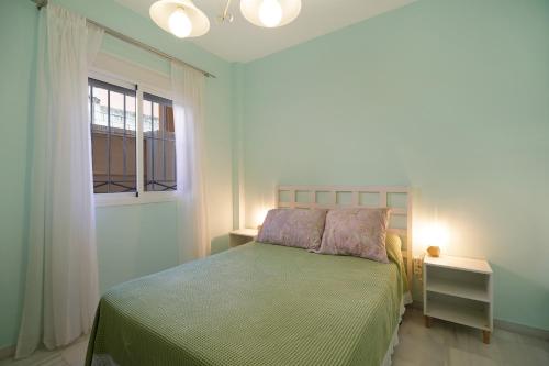 a bedroom with a bed with a green bedspread and a window at San jeronimo in Sanlúcar de Barrameda