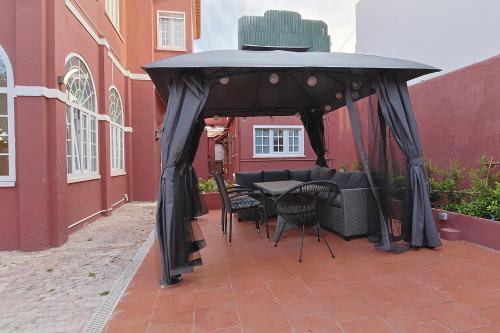 a black gazebo with a table and chairs under it at Vila Olivença in Costa da Caparica