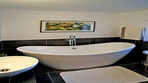 uma grande banheira branca numa casa de banho com lavatório em Doonreagan West Wing, Cashel em Canower