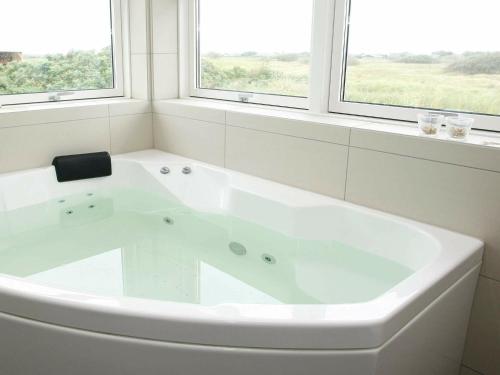 a white bath tub in a bathroom with two windows at 8 person holiday home in L kken in Løkken