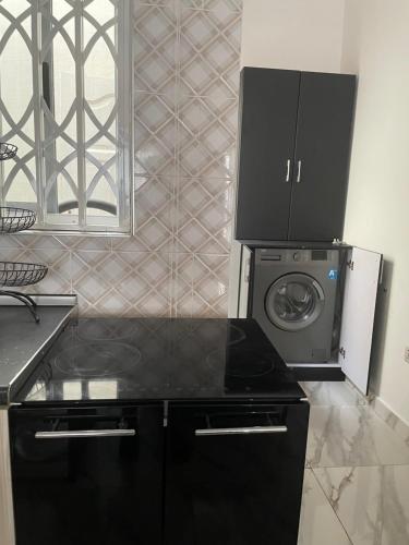a kitchen with a black counter top and a washing machine at Newly built house in Accra in Danfa