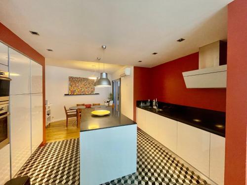 une cuisine avec des placards blancs et un mur rouge dans l'établissement Le Bonrepos - T3 sur les Ramblas de Toulouse, à Toulouse