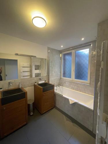 La salle de bains est pourvue de 2 lavabos, d'une baignoire et d'une fenêtre. dans l'établissement Le Bonrepos - T3 sur les Ramblas de Toulouse, à Toulouse