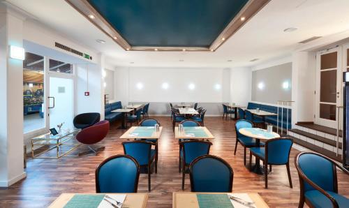 a restaurant with tables and chairs in a room at Living Hotel am Olympiapark in Munich