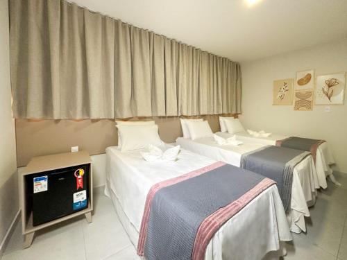 a hotel room with three beds and a tv at Hotel Haki in Patos