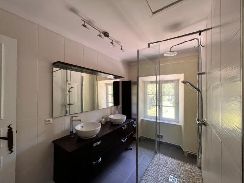 ein Badezimmer mit zwei Waschbecken und einer Glasdusche in der Unterkunft Bergerie de l'Horte in Tourouzelle