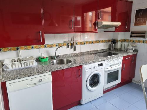 a kitchen with red cabinets and a washing machine at Piso zona hospital 7 personas in Oviedo
