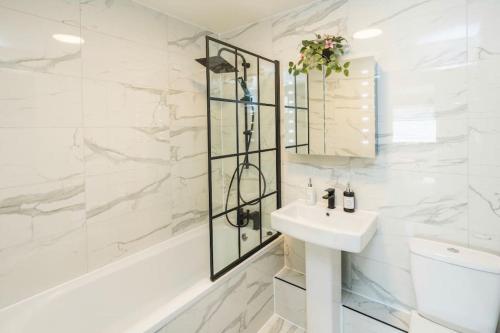 a white bathroom with a sink and a shower at Smart Living Sophisticated Style - Photo ID & Deposit Required in London