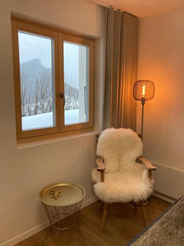 a living room with a white chair and a window at Le Lézard et la Grenouille BnB in Ovronnaz