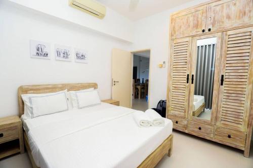 a bedroom with a large white bed and a wooden cabinet at Brand New Luxury apartment in Galle, offering true comfort and relaxation in Galle