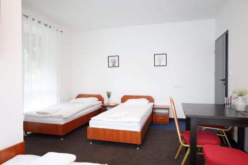 2 Betten in einem Zimmer mit einem Schreibtisch und einem Tisch in der Unterkunft Zakarczmie Stokrotka in Leżajsk