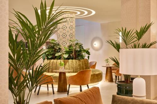 a lobby with plants and tables and chairs at Barceló Carmen Granada in Granada