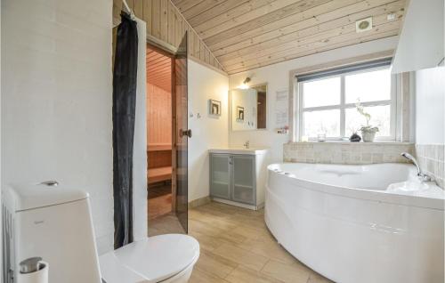 La salle de bains est pourvue d'une grande baignoire et de toilettes. dans l'établissement Nice Home In Ebeltoft With 4 Bedrooms, Sauna And Wifi, à Ebeltoft