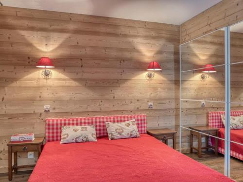 ムジェーヴにあるAppartement Megève, 2 pièces, 4 personnes - FR-1-453-125の赤いベッドと木製の壁が備わるベッドルーム1室が備わります。