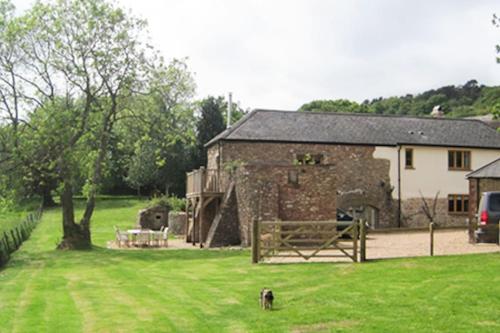 a dog standing in the grass in front of a building at Luggs Barn - Beautiful Devon Hideaway in Hemyock