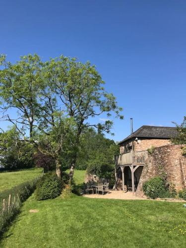 an old stone house with a table and a tree at Luggs Barn - Beautiful Devon Hideaway in Hemyock