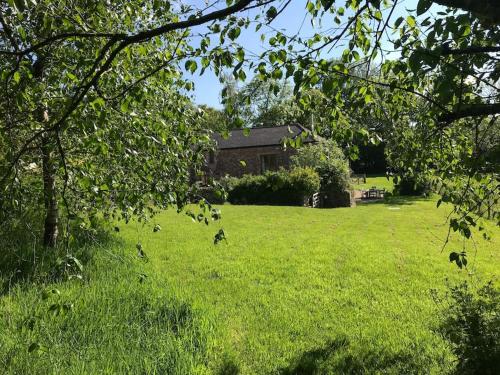 a field of grass with a house in the background at Luggs Barn - Beautiful Devon Hideaway in Hemyock