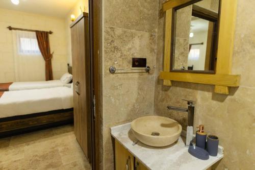ein Bad mit einem Waschbecken, einem Spiegel und einem Bett in der Unterkunft Cappalace Stone House in Ürgüp