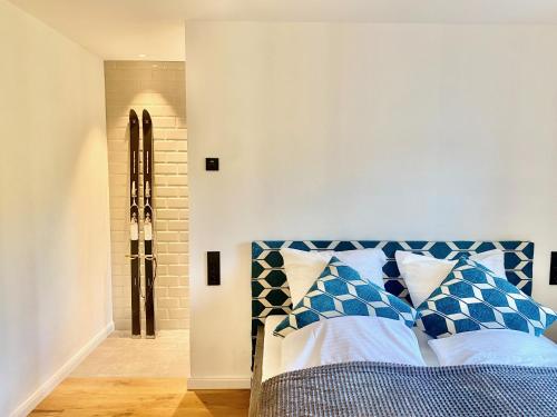 Snug Stays Design Villa mit Garten zentral aber ruhig 400m zum Ammersee في ديسن آم أميرسي: غرفة نوم مع سرير ووسائد زرقاء وبيضاء