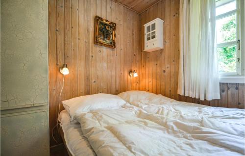 a bed in a bedroom with a wooden wall at Awesome Home In Ebeltoft With 3 Bedrooms in Ebeltoft