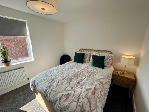 1 dormitorio con 1 cama con mesita de noche y ventana en Salford Townhouse 3 BR Home en Mánchester