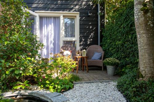 un patio avec une table et des chaises et un chien assis sur une chaise dans l'établissement B&B Joli met privé wellness, à Wemeldinge