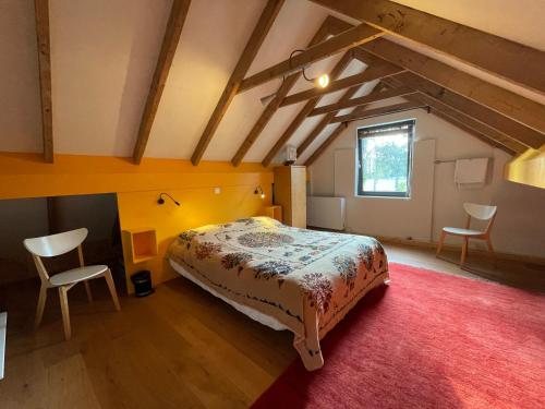 een slaapkamer met een bed en 2 stoelen op een zolder bij vakantieverblijf Marke Lemselo in Weerselo