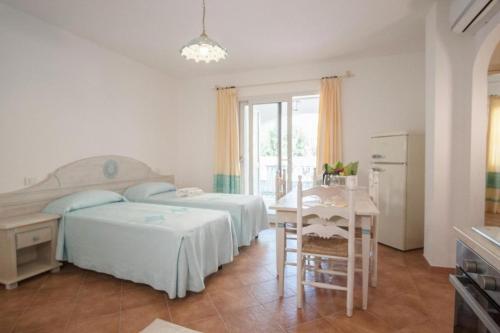a bedroom with two beds and a table and a kitchen at Superb Le Residenze del Golfo di Orosei num2192 in Orosei