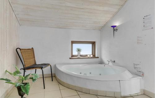 3 Bedroom Nice Home In Ebeltoft في إيبلتوفت: حمام أبيض مع حوض استحمام وكرسي