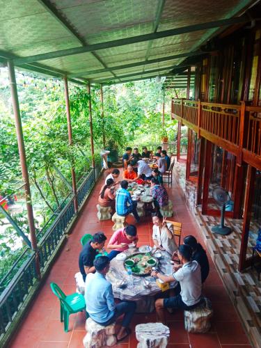 a group of people sitting at tables on a porch at homestay phô núi suôi giang in Yên Bái